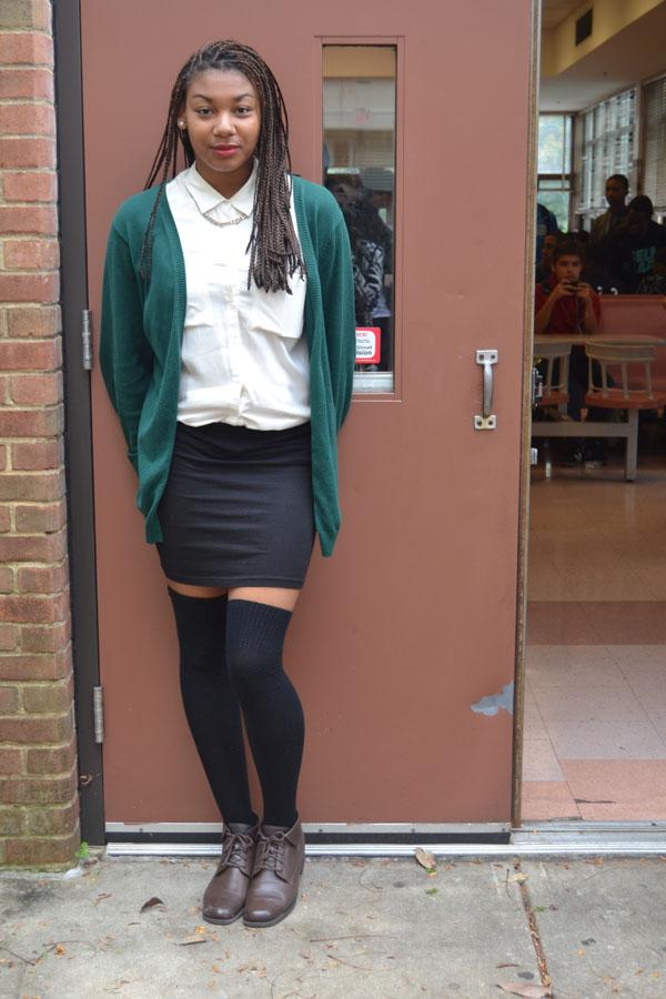 Senio, Armani Smith makes a fashion statement with this get together. She is wearing a loose fitting button up white blouse, a fitted black skirt, over-the-knee black socks, topped with a deep green warm olive cardigan.